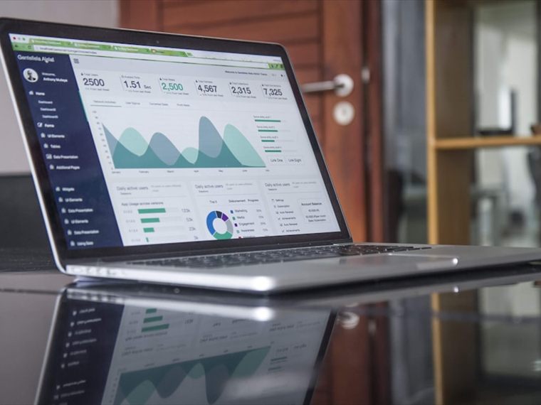 A laptop displaying a financial dashboard of charts and performance figures