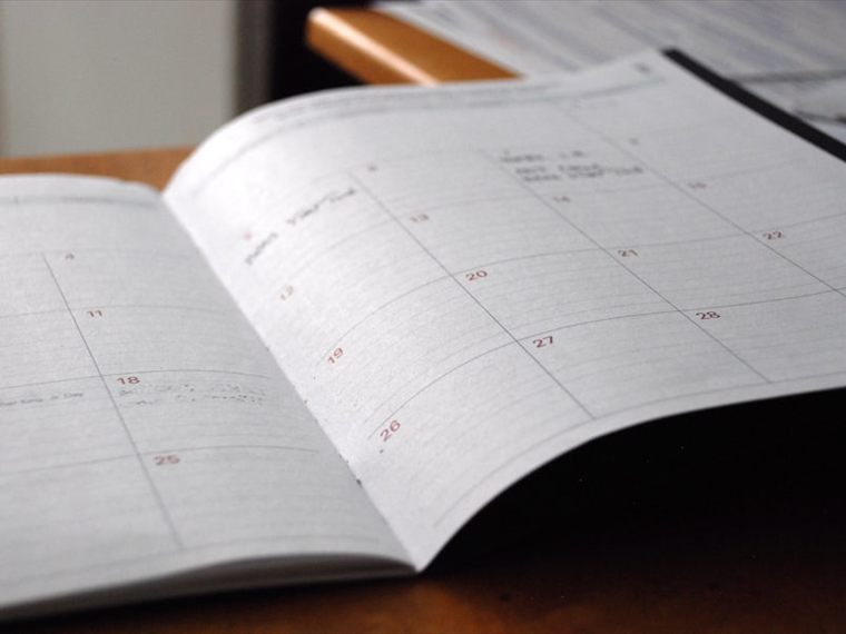 An open month-view planner on a desk, used for mapping out deadlines ahead